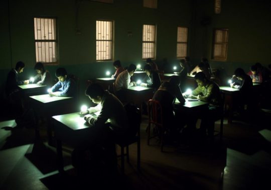 "Estudiantes estudiando en una escuela oscura, iluminados por sombras precisas y luminosas."