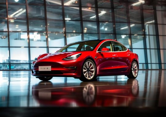 "Un Tesla Model 3 rojo con puertas de vidrio y grandes ventanas, capturado en un estilo reminiscente de Kodak Aerochrome, con tonos de púrpura claro y bronce claro, y un diseño industrial destacado por pinceladas dinámicas en blanco oscuro y rojo claro."