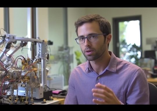 Un hombre con gafas hablando a través de un aparato en un ambiente de ciencia, capturado en una película de baja velocidad.