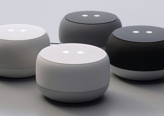 "Tres altavoces Google Home dispuestos sobre una superficie blanca, presentados como objetos 3D luminosos en un estilo futurista y funky, con un enfoque en el botón trasero, en tonos oscuros, blancos y negros."