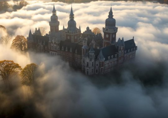 "Un castillo envuelto en una misteriosa niebla otoñal, destacando su opulenta arquitectura, evocando el estilo visual de Frieke Janssens, Wes Anderson y Hiroshi Katsuragawa."